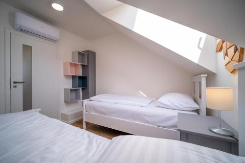 a white bedroom with two beds and a window at Holiday House U Hájenky 5L Lipno Home in Lipno nad Vltavou