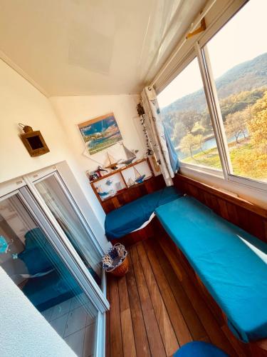 Cette chambre dispose d'un canapé bleu et d'une grande fenêtre. dans l'établissement Spacieux Appartement Climatisé  Dernier étage, à Agay