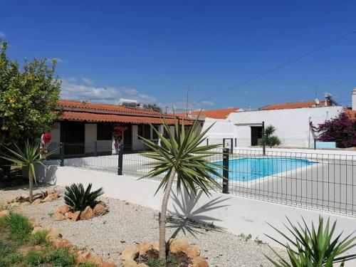 a house with a fence around a swimming pool at Quinta Cosy in Paderne