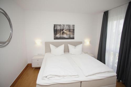 1 dormitorio con 1 cama blanca con sábanas y almohadas blancas en strandnah mit Terrasse, gratis Nutzung vom AHOI Erlebnisbad und Sauna in Sellin - Strandhaus Mönchgut FeWo06, en Lobbe
