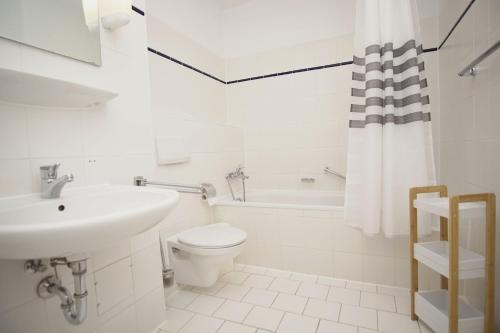 a white bathroom with a sink and a toilet at strandnah mit Terrasse, gratis Nutzung vom AHOI Erlebnisbad und Sauna in Sellin - Strandhaus Mönchgut FeWo06 in Lobbe