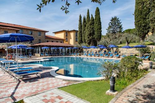 une grande piscine avec des parasols et des chaises bleus dans l'établissement Hotel Villa Paradiso, à Passignano sul Trasimeno