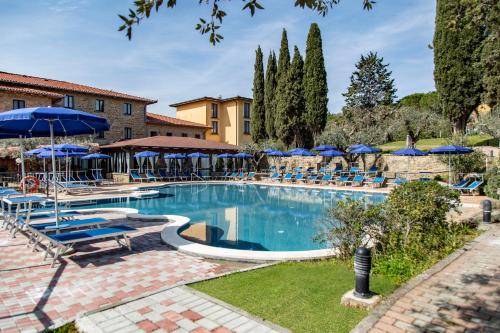 a large swimming pool with blue umbrellas and chairs at Hotel Villa Paradiso in Passignano sul Trasimeno