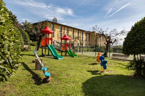 a playground with play equipment in the grass at Hotel Villa Paradiso in Passignano sul Trasimeno