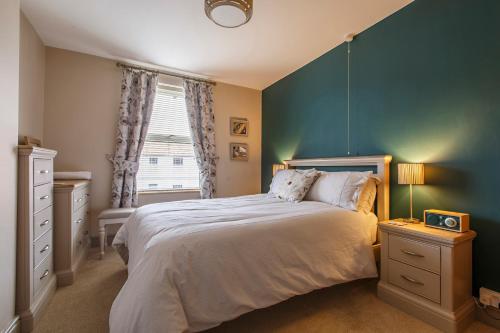 a bedroom with a large bed and a blue wall at Mabel Cottage Sheringham in Sheringham