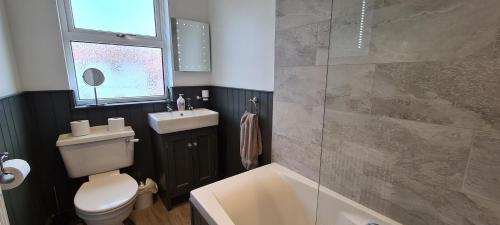 a bathroom with a toilet and a sink and a shower at Mabel Cottage Sheringham in Sheringham