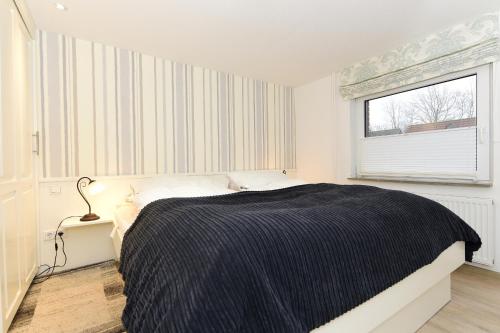 a white bedroom with a bed and a window at Haus Kiehlwasser Whg 02 EG in Boldixum