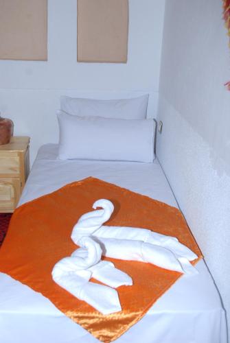 a bed with an orange blanket with a towel on it at Dar Mezyana Dades in Aït Idaïr