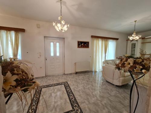 a living room with a white couch and a chandelier at Myrtia Guest House in Pýrgos