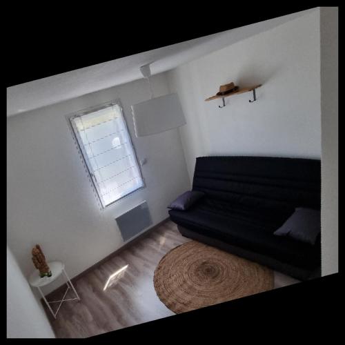 sala de estar con sofá negro y ventana en Maison de vacances Torreilles plage 6 personnes, en Torreilles