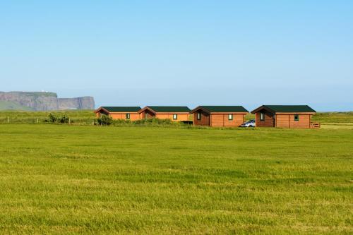 a grassy field with a house and some buildings at Mid Hvoll Cottages in Suður Hvoll