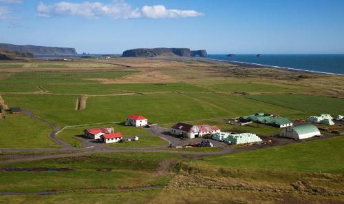 an aerial view of a field with houses and the ocean at Mid Hvoll Cottages in Suður Hvoll