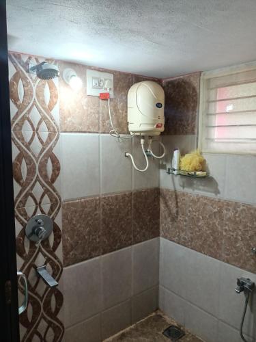uma casa de banho com um chuveiro e um secador de cabelo na parede em Tavaru home stay em Ankola