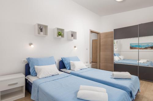 a bedroom with two blue beds and a mirror at Apartment DANI-E.L. in Kastav