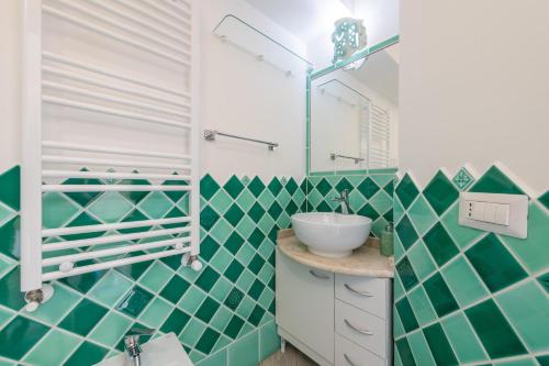 a bathroom with green and white tiled walls and a sink at Luxury Apartment Simius in Villasimius