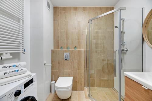 a bathroom with a shower and a toilet and a sink at BURSZTYNOVA Apartamenty Piamola in Kąty Rybackie