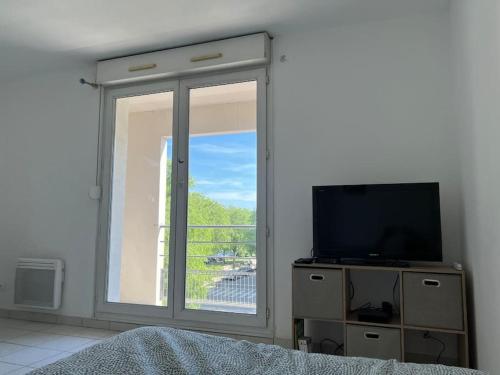 a bedroom with a tv and a large window at Le Studio 36 à Nîmes, Wifi, Balcon in Nîmes
