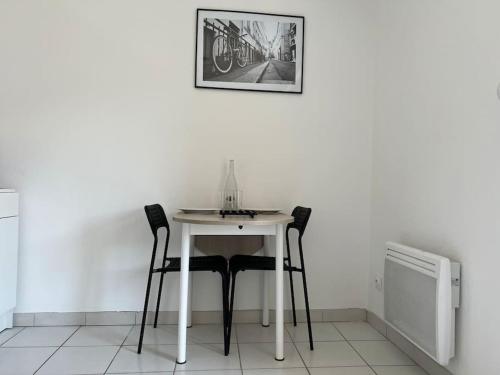 a white table with two chairs and a picture on the wall at Le Studio 36 à Nîmes, Wifi, Balcon in Nîmes