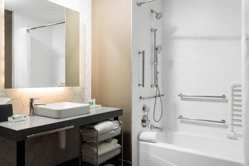 a bathroom with a sink and a tub and a shower at Holiday Inn & Suites Nashville Downtown Broadway in Nashville