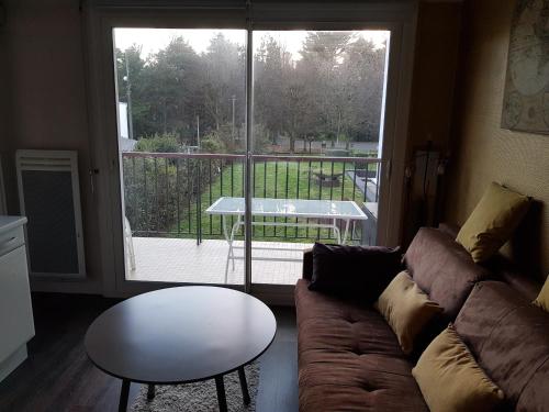 - un salon avec un canapé, une table et une grande fenêtre dans l'établissement 20ml du port, au Pouliguen