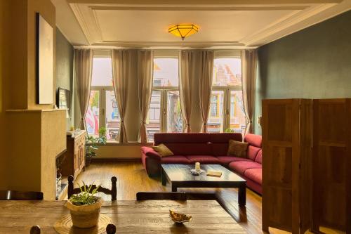 a living room with a red couch and a table at Gunnery's Guest House in Alkmaar