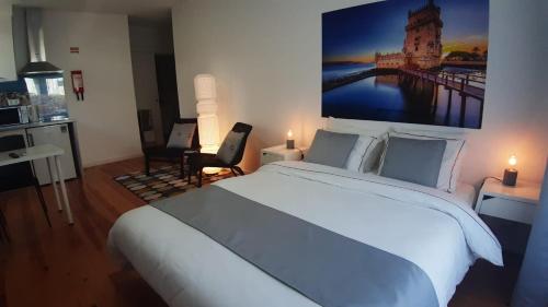 a bedroom with a large white bed with a large painting on the wall at Real Home in Sacavém
