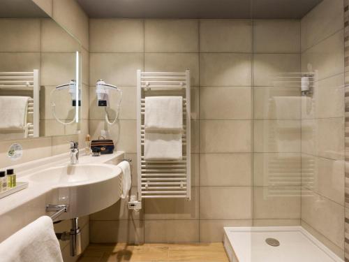une salle de bain avec un lavabo et une douche dans l'établissement Hôtel Roi Soleil Prestige Plaisir - St Quentin, à Plaisir
