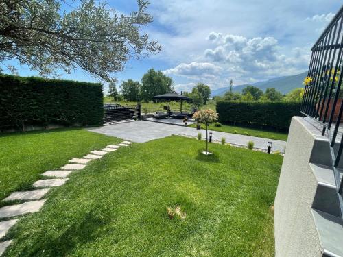a backyard with a lawn with a table and an umbrella at Meteora vibes in Kalabaka