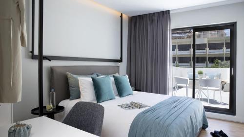 a bedroom with a bed and a view of a balcony at The Alex Monte Kastella, Santikos Collection in Piraeus
