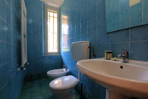a blue tiled bathroom with a sink and a toilet at Bed & Parking Cecina Rooms in Cecina