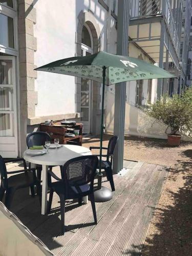 - une table et des chaises avec un parasol vert sur la terrasse dans l'établissement Appartement Résidence les pieds dans l'eau Croisic, au Croisic