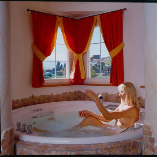 a woman is sitting in a bath tub at Nature Wellness Hotel Renato in Vigo di Fassa