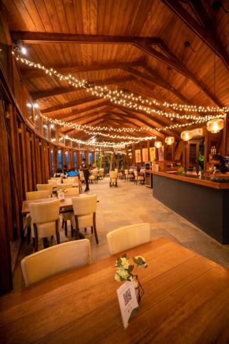 a dining room with lights and tables and chairs at Houttuyn Wellness River Resort in Paramaribo