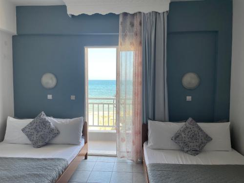 two beds in a room with a view of the ocean at Nisel Seaside in Paralia Katerinis