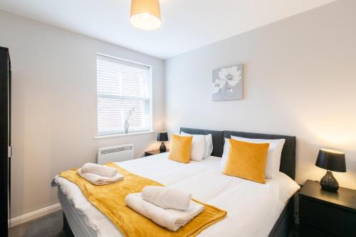 een slaapkamer met een groot wit bed met gele kussens bij Velvet 2-bedroom apartment, Brewery Road, Hoddesdon in Hoddesdon
