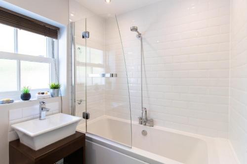 a white bathroom with a sink and a shower at Velvet 2-bedroom apartment, Brewery Road, Hoddesdon in Hoddesdon