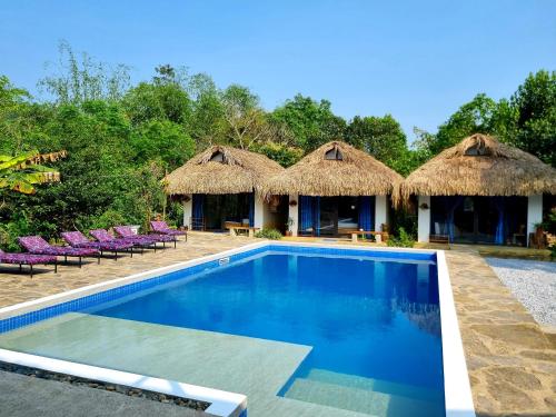 un complexe avec une piscine et des cabanes au toit de chaume dans l'établissement NoMadders Ha Giang, à Ha Giang
