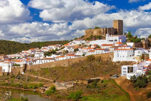 a group of white buildings on a hill next to a river at Casa da Cerca in Corte do Pinto