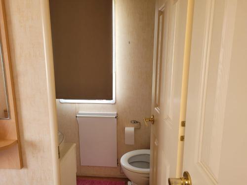 a small bathroom with a toilet and a window at 6 Berth Sealands Ingoldmells Free WIFI Westmorland SL in Ingoldmells