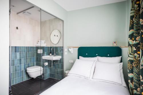a bathroom with a bed and a shower and a toilet at Hôtel AMI - Orso Hotels in Paris