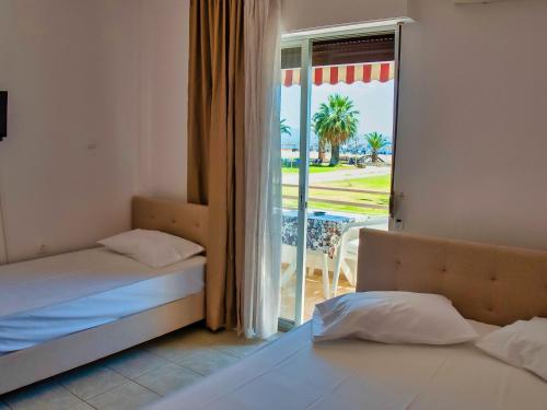 two beds in a room with a view of the ocean at Prassas Sea View in Nea Potidaea