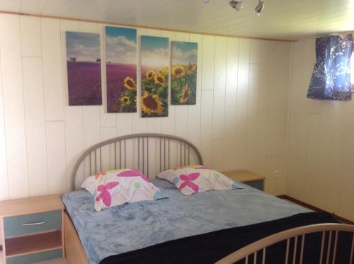 1 dormitorio con 1 cama con 2 almohadas y pinturas en la pared en Le p'tit de l'Ecureuil, en Sougné-Remouchamps