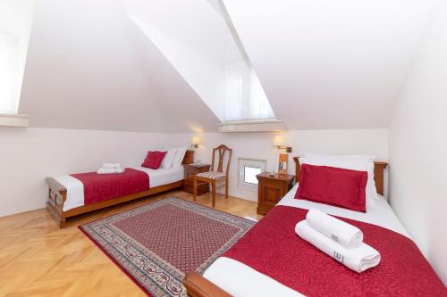 a bedroom with two beds with red and white sheets at Heritage Hotel Tisno in Tisno