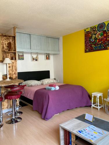 a bedroom with a purple bed and yellow walls at Le Studio Victoria II -Mon Desert Village -27m2 in Nancy
