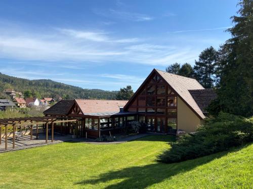 a large house with a large yard with green grass at LE CLOS DES SOURCES Hôtel & Spa in Thannenkirch