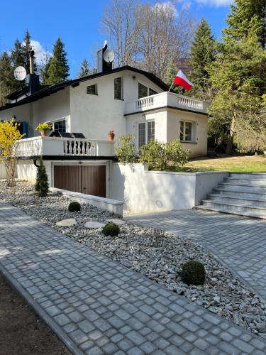 a white house with a porch and a driveway at Osada Parkowa, Kaszuby in Mściszewice