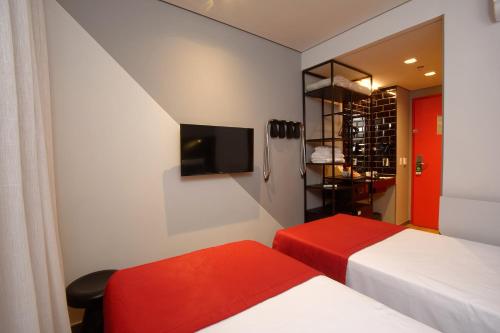 a hotel room with two beds and a tv at Golden Tower Express Berrini by Fênix Hotéis in São Paulo