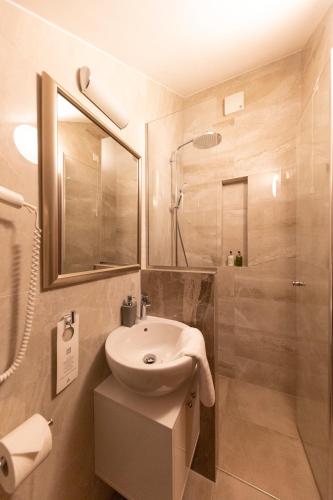 a white bathroom with a sink and a shower at Heritage Hotel Tisno in Tisno