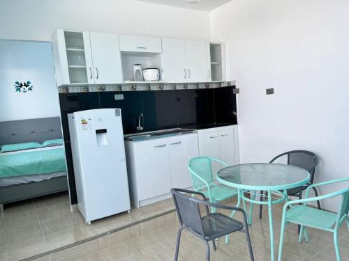 a kitchen with a table and chairs and a refrigerator at Hermoso mini departamento c/ entrada independiente in Piura
