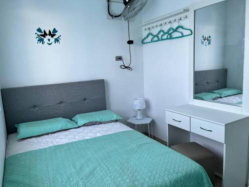 a bedroom with a green bed and a mirror at Hermoso mini departamento c/ entrada independiente in Piura